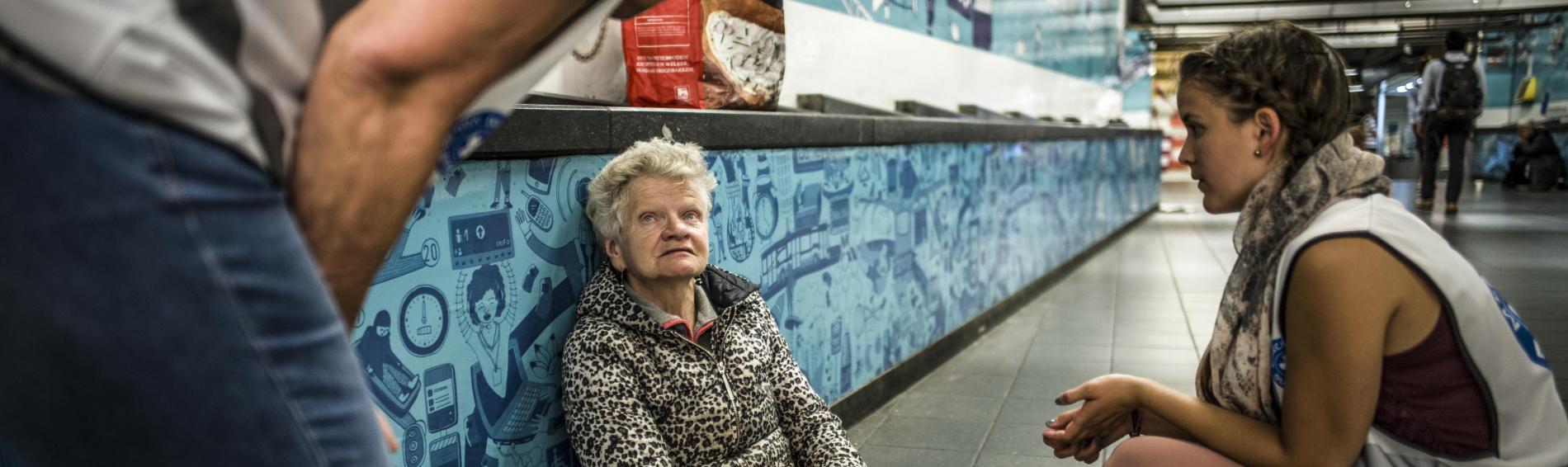 Dans les couloirs de la Gare Centrale, deux bénévoles de Médecins du Monde discutent avec un femme assise par terre.